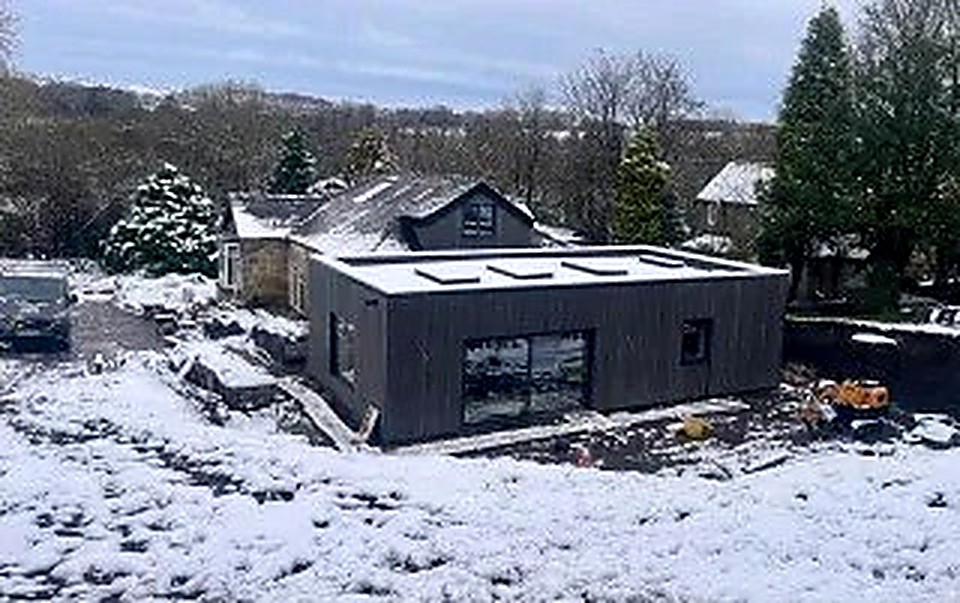 Dark-clad low-energy extension with skylights in a snowy Derbyshire landscape