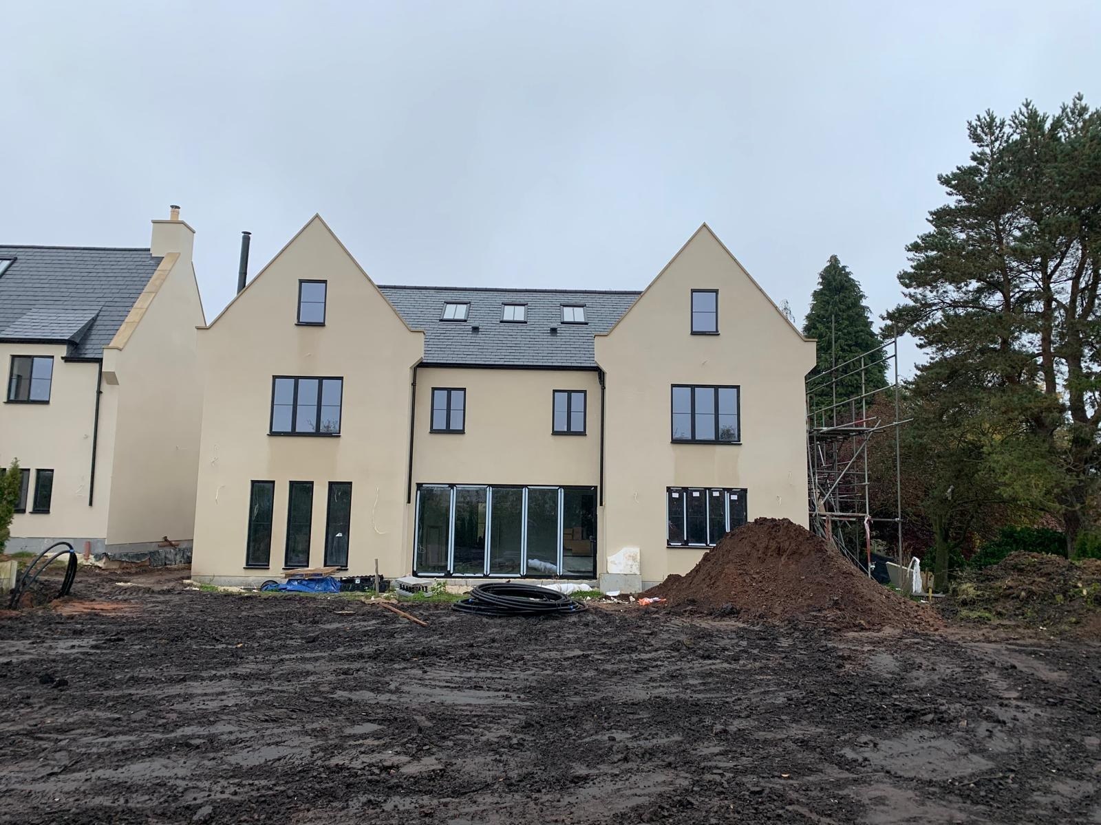 Front elevation of a gabled luxury new build with rendered walls and black window frames, Chesterfield