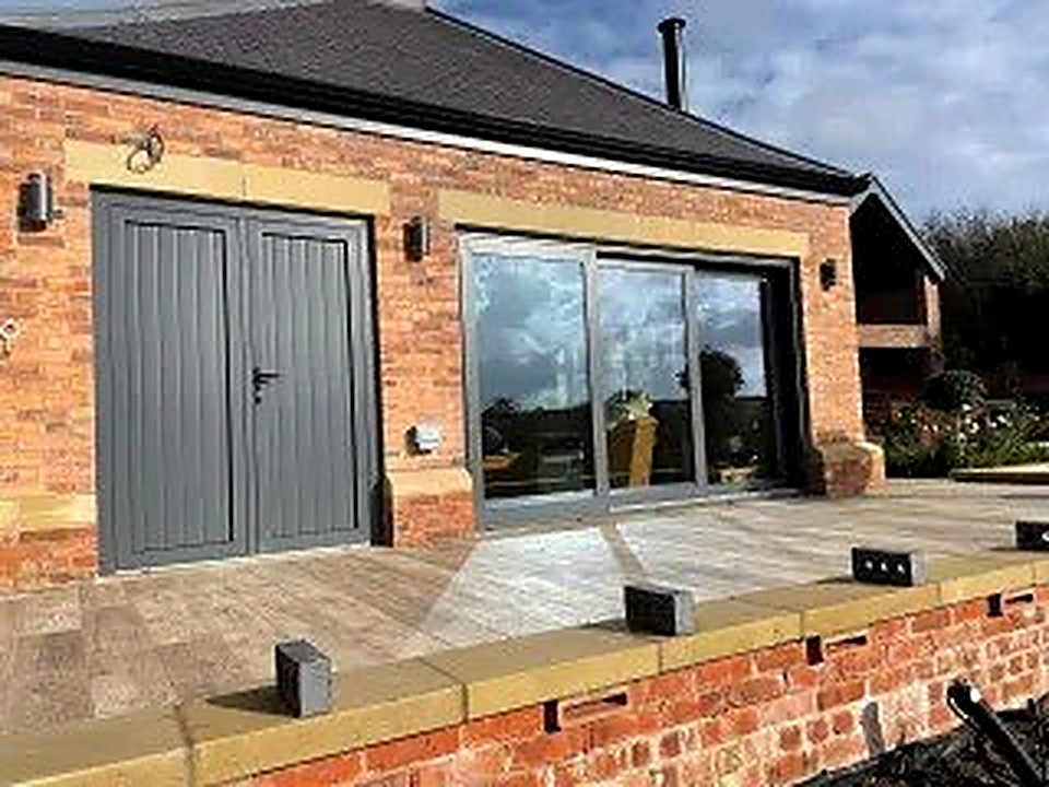 Brick rear extension in Chesterfield with large grey sliding doors onto a paved patio