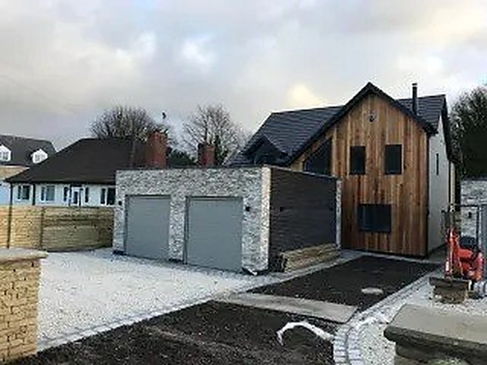 Low-energy home with stone cladding, vertical timber siding and double garage in Derbyshire