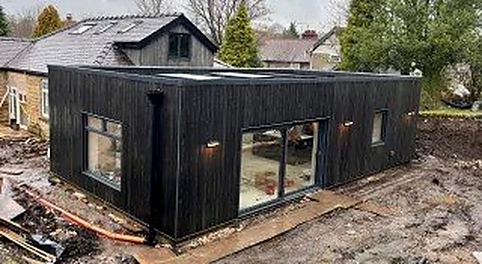 Black timber-clad passive house extension with large sliding glazing, Derbyshire