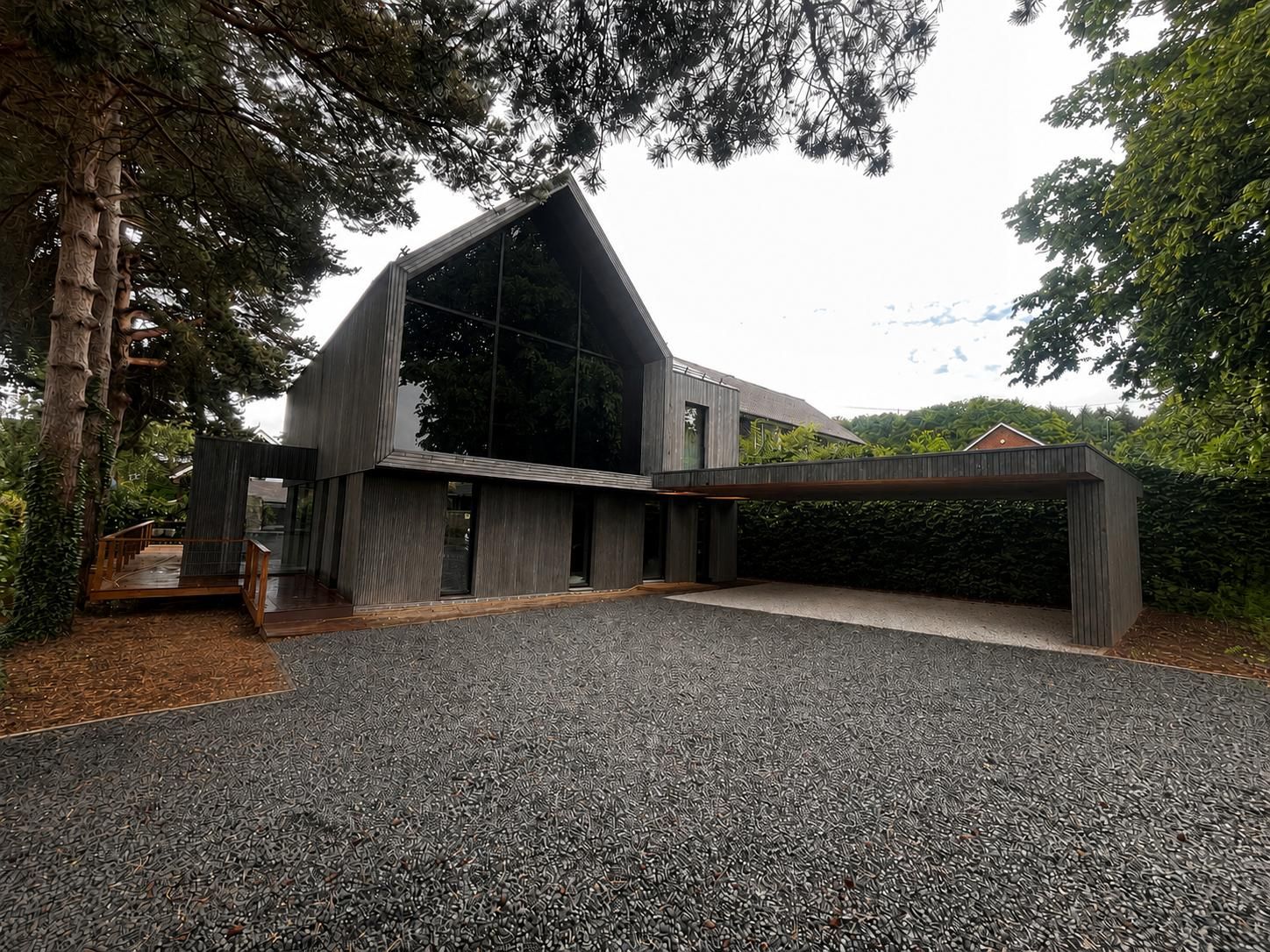 Completed timber-clad architect-designed home with full-height gable glazing, resin driveway and carport, Derbyshire