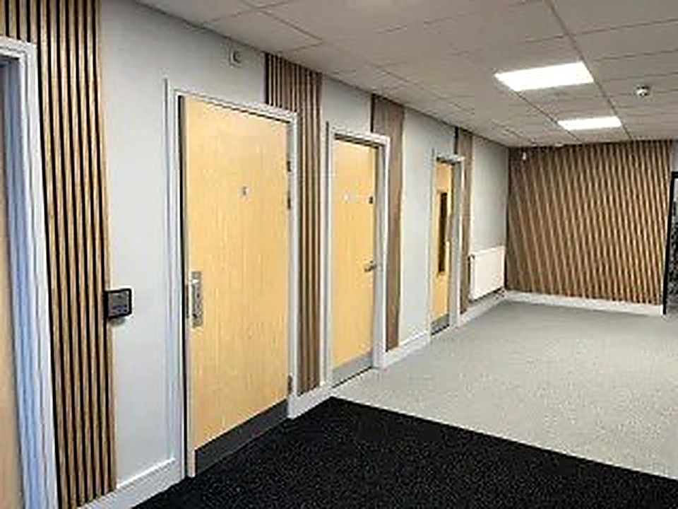 Refurbished corridor with light timber doors and vertical slat wall panelling, Derbyshire