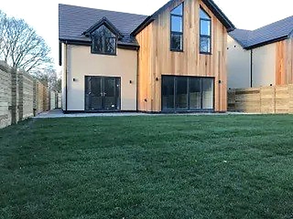 Contemporary new build house with off-white render and vertical timber cladding in Derbyshire