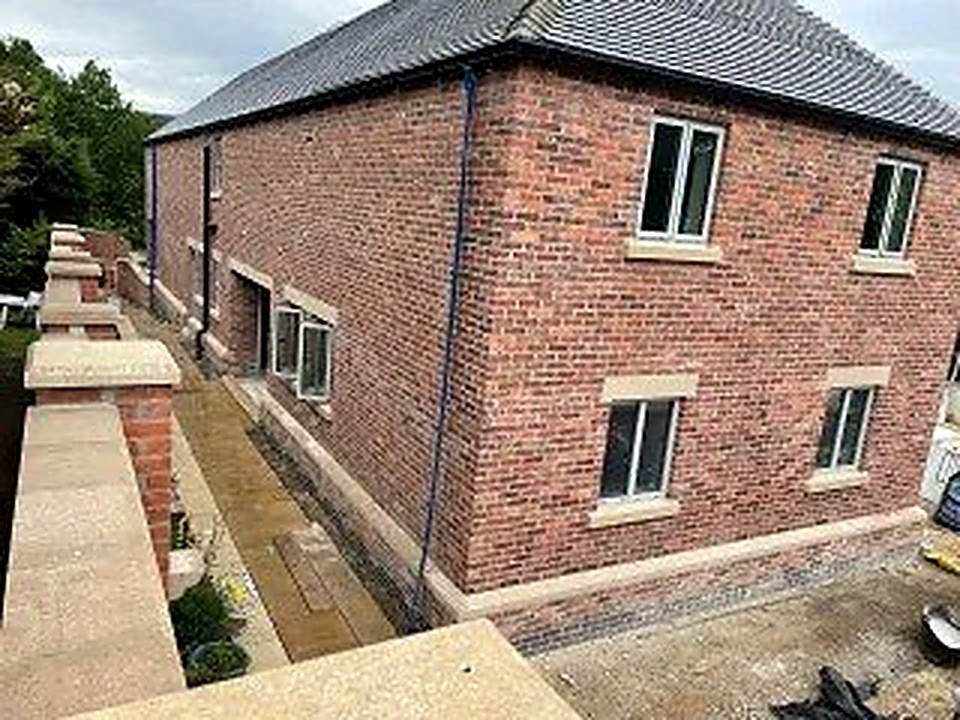 Two-storey red brick new build with natural stone window surrounds near Chesterfield