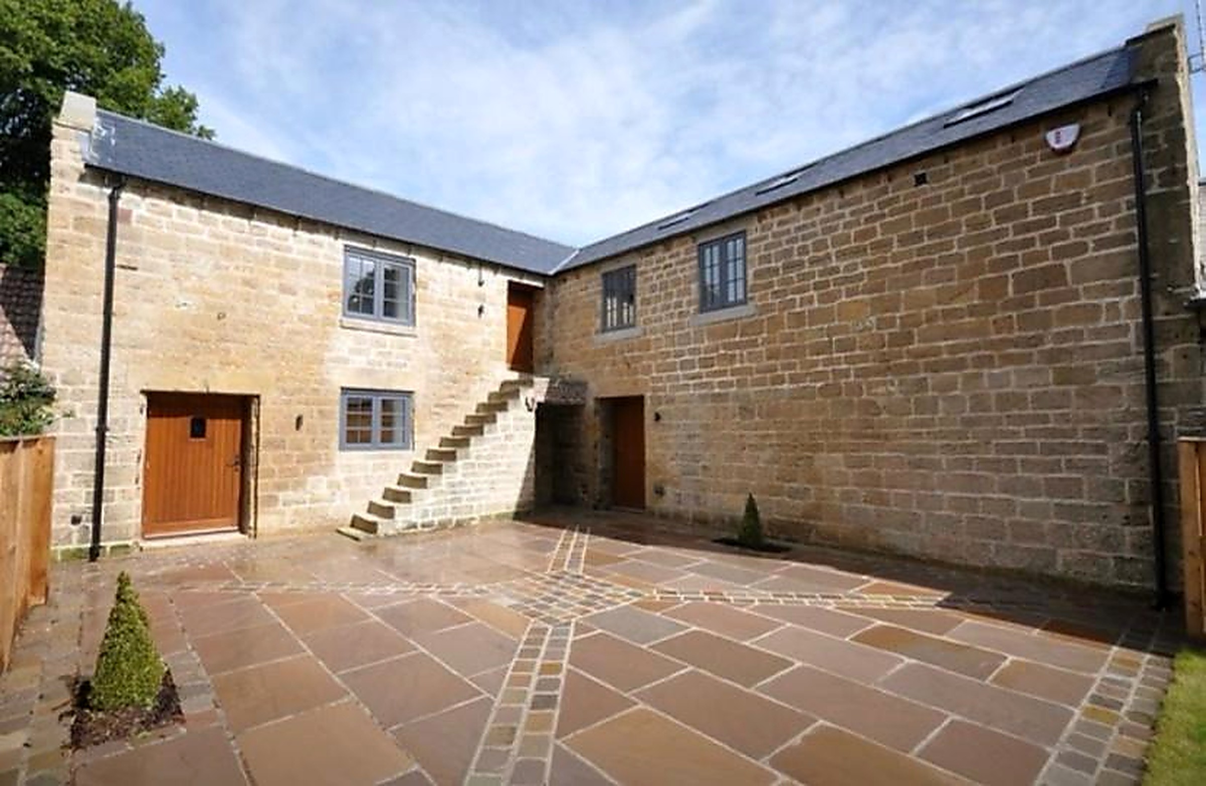 L-shaped stone barn conversion with external stone staircase and paved courtyard in the Peak District