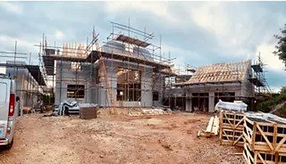 Luxury house under construction with timber roof framing and full scaffolding in Chesterfield